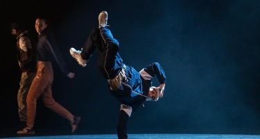 A dancer balances on one hand, with their legs raised in the air.