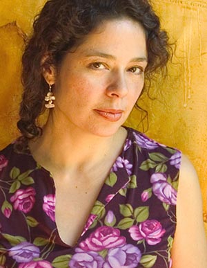Portrait of Sandra Laronde wearing floral shirt, framed against yellow background.