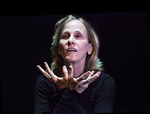 Portrait of Deborah Colker with hands open palm upwards towards face.