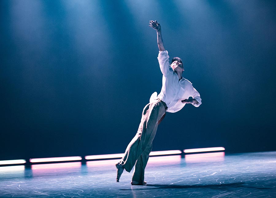 Dancer in billowing white shirt with arm raised.