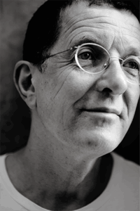 Portrait of a man in glasses and a white t-shirt facing slightly to the right.