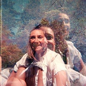 Jeanette Kotowich. A grainy image of a smiling woman in a white, short sleeve blouse. Three other portraits of her are overlaid in transparent layers.