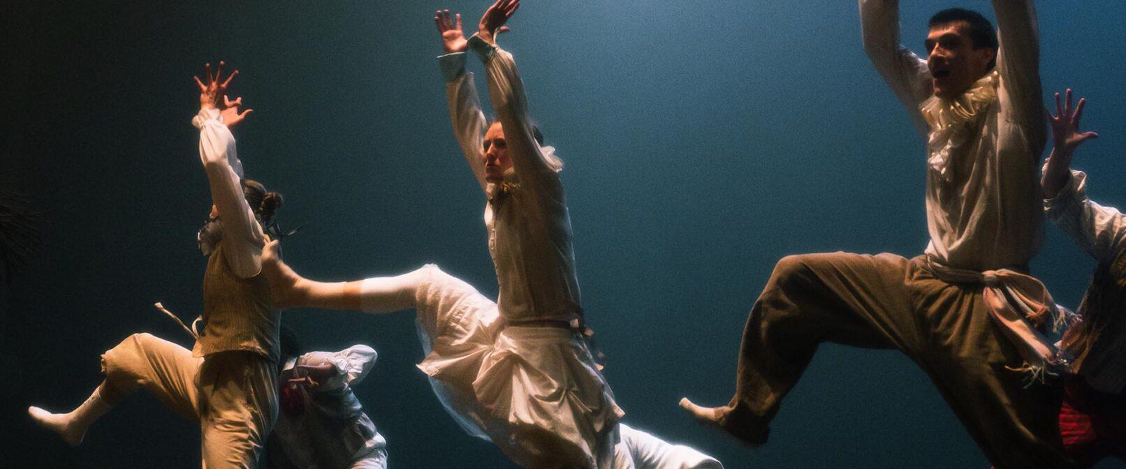 Hofesh Shechter Company. Three men leap with arms raised and one foot in the air.