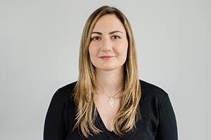 Jada Tellier. Portrait photo of a light skinned woman with long, blonde hair. She is wearing a long sleeve black top and a necklace.