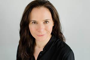 Paula Meyler. Portrait photo of a light skinned woman with long, brown hair and brown eyes. She is wearing a long sleeve, black top.